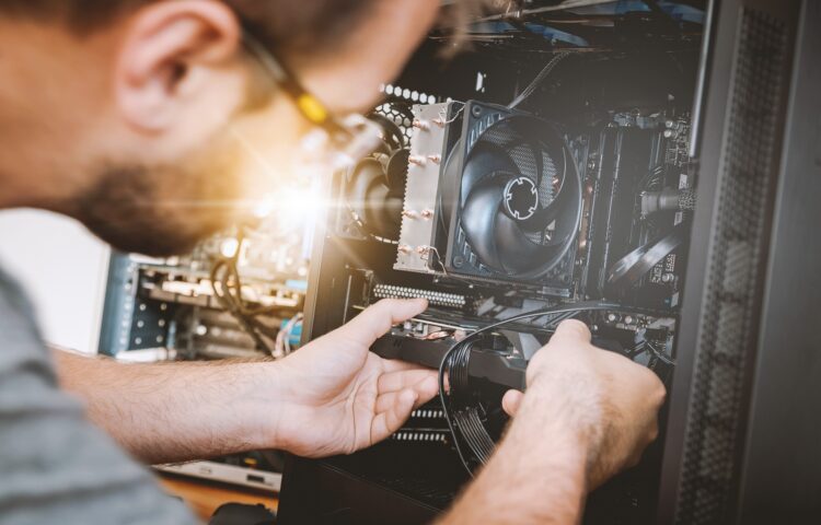 Technicien réparant l’intérieur d’un ordinateur pro reconditionné, vérifiant les composants et les câbles